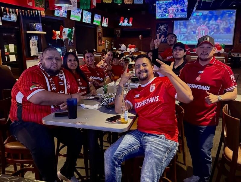 Red Jersey Crew: A table of fans in red jerseys cheering on the game.