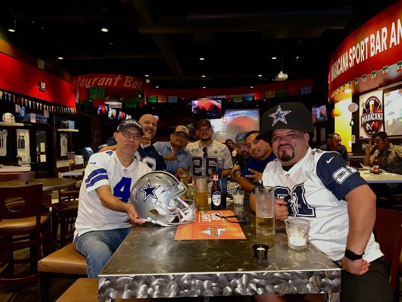 Cowboys Crew: A table of Cowboys fans with a helmet on the table.
